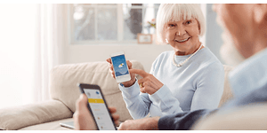 Ett äldre par visar varandra något på sina smartphones.