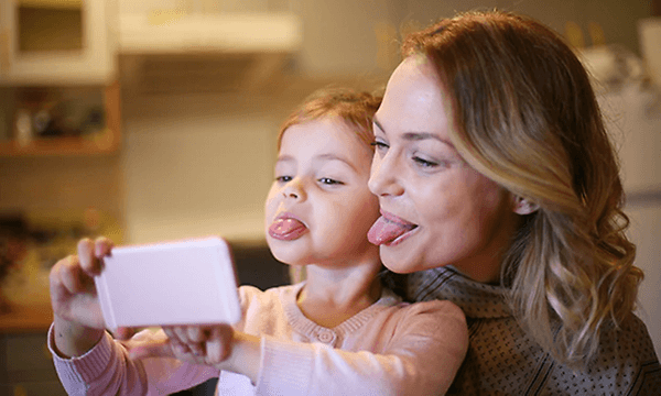 Mor och dotter tar selfie av fula miner i mobiltelefonen.