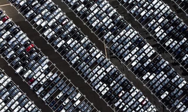 Bild tagen ovanifrån på en stor bilparkering utomhus med flera hundra bilar.
