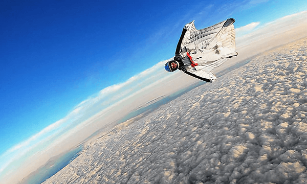 Man i en vit så kallad wingsuit, flyger ovan molnen. 