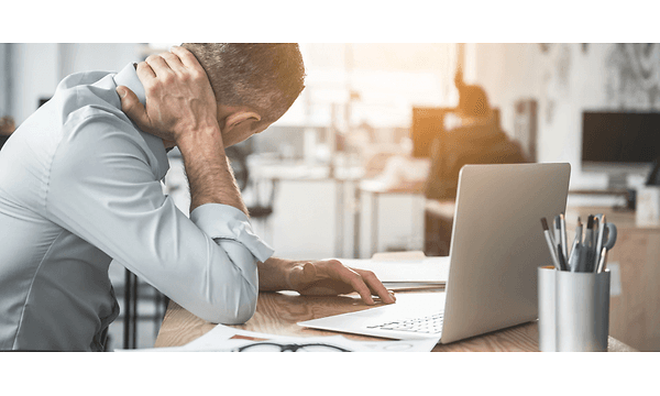 en mand med tydelig ondt i nakken arbejder på sin bærbare compute