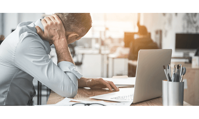 en mand med tydelig ondt i nakken arbejder på sin bærbare compute