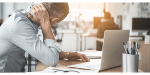 en mand med tydelig ondt i nakken arbejder på sin bærbare compute