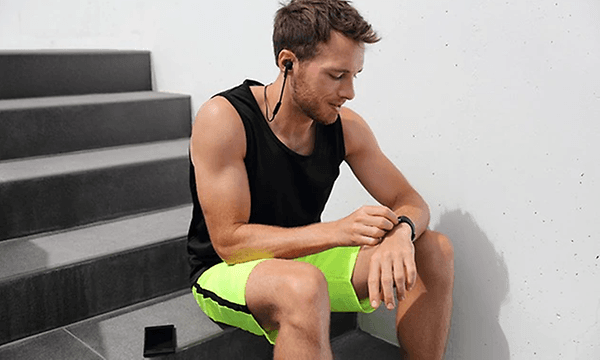 En man tar en paus från sin träning och ser på sin smartwatch.