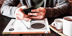 nærbilde av person som bruker smarttelefon på kafé