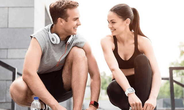 Par der binder deres sko med headset og sportsur på