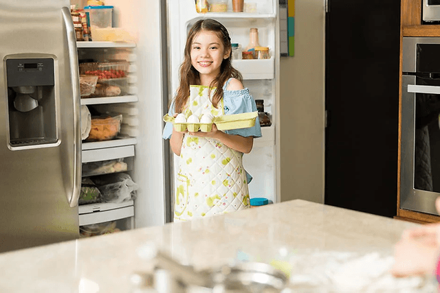 girl getting eggs from the two door refrigerator