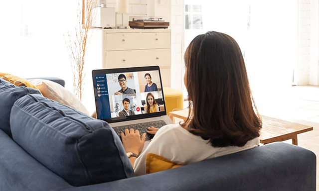 kvinne har et videomøte på laptop i sofa hjemme