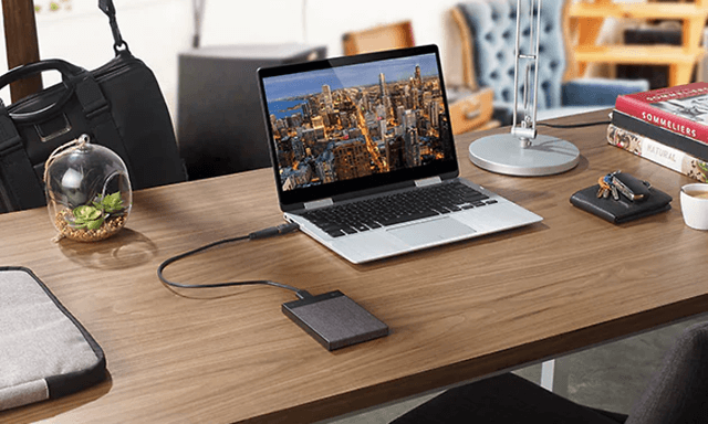 laptop og ekstern harddisk koblet sammen på et bord på hjemmekontor