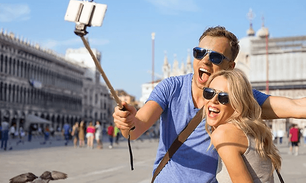 Pariskunta ottamassa valokuvaa ulkona selfiekepillä