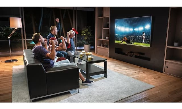 Mænd i en stue der ser TV på en stor skærm