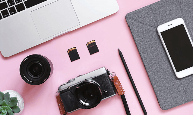Photo equipment and mac and iphone laying on a pink table