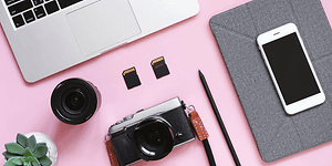 Photo equipment and mac and iphone laying on a pink table